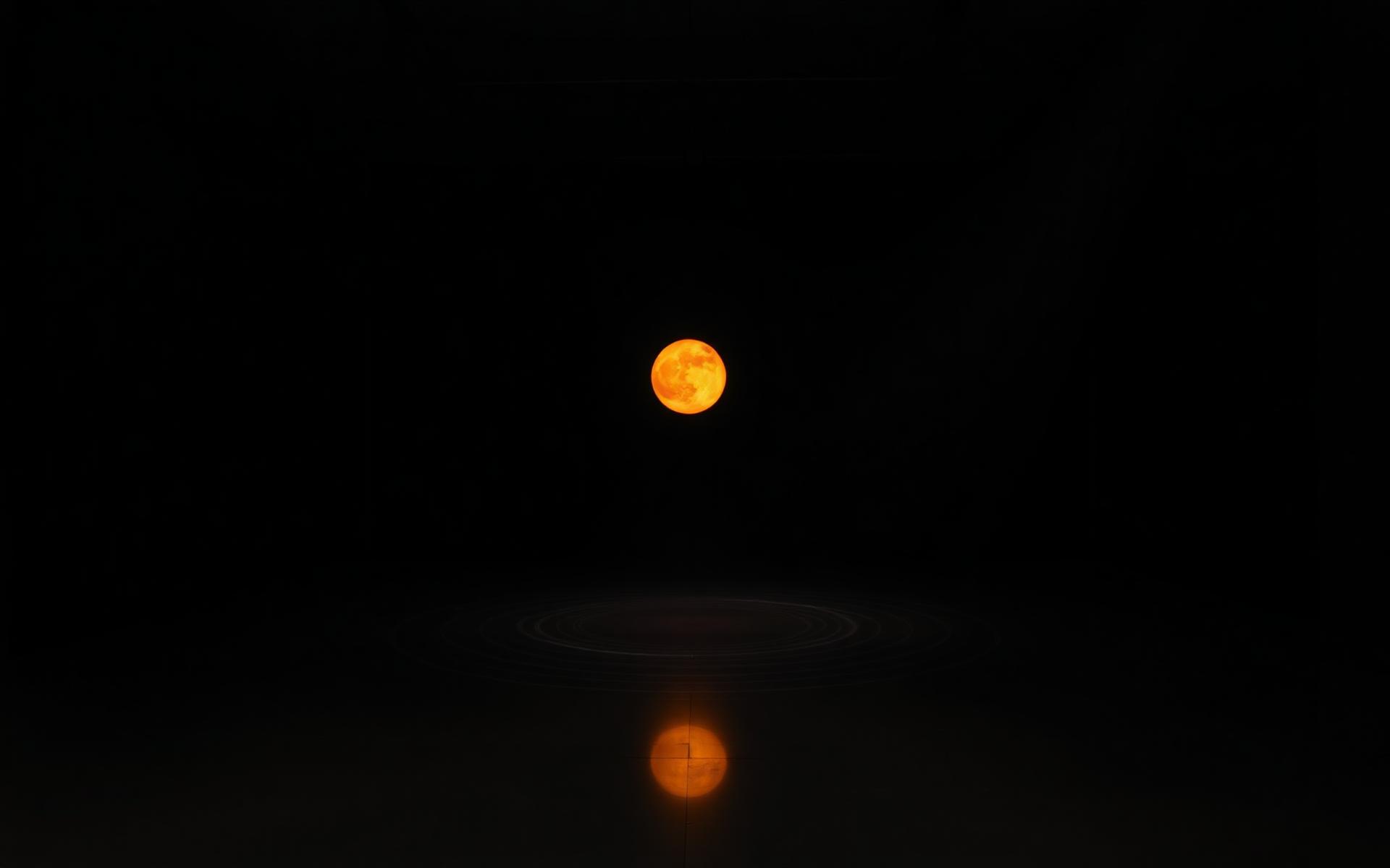 Glowing amber sphere suspended in a dark gallery — Flowtasia installation